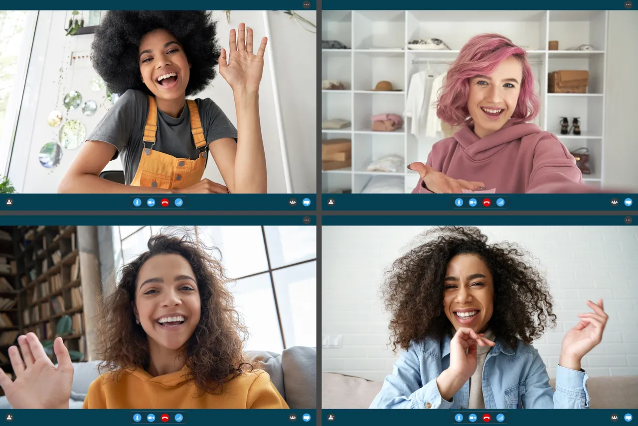 Four women smiling and waving during a video call, representing virtual workplace friendships and connection among remote team members.